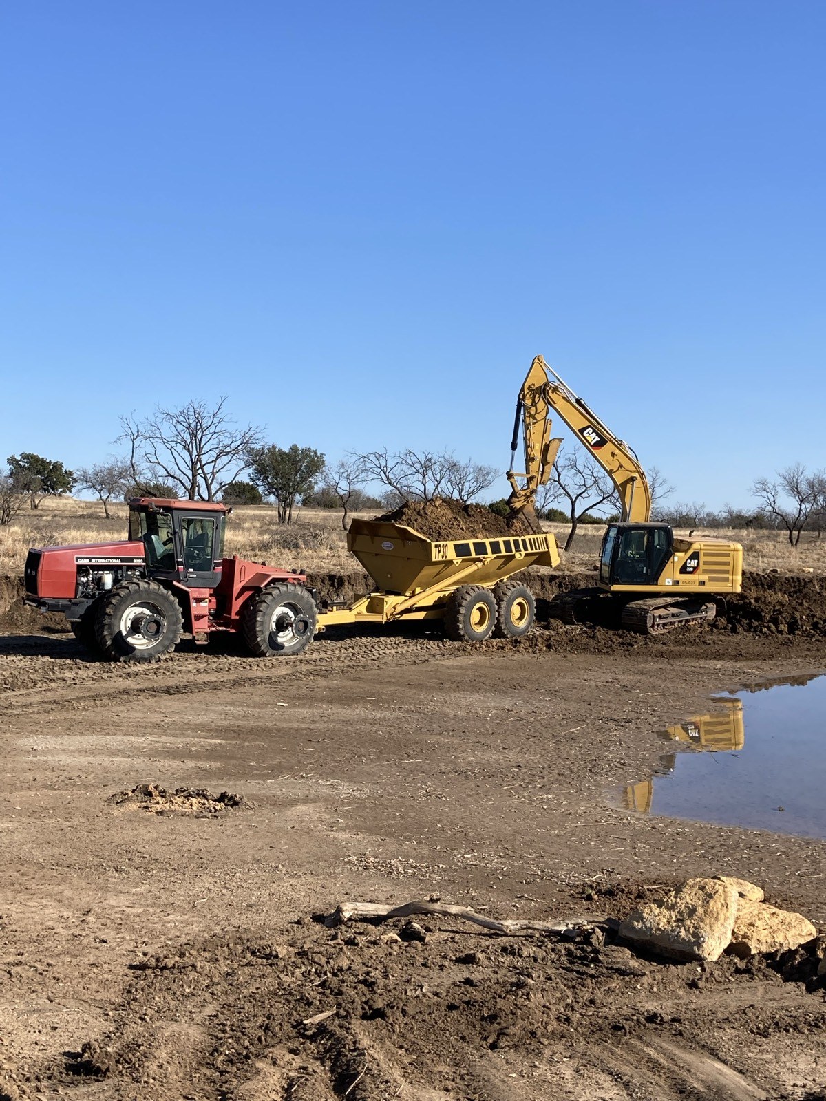 Tractor and dump wagon being loaded by excavator