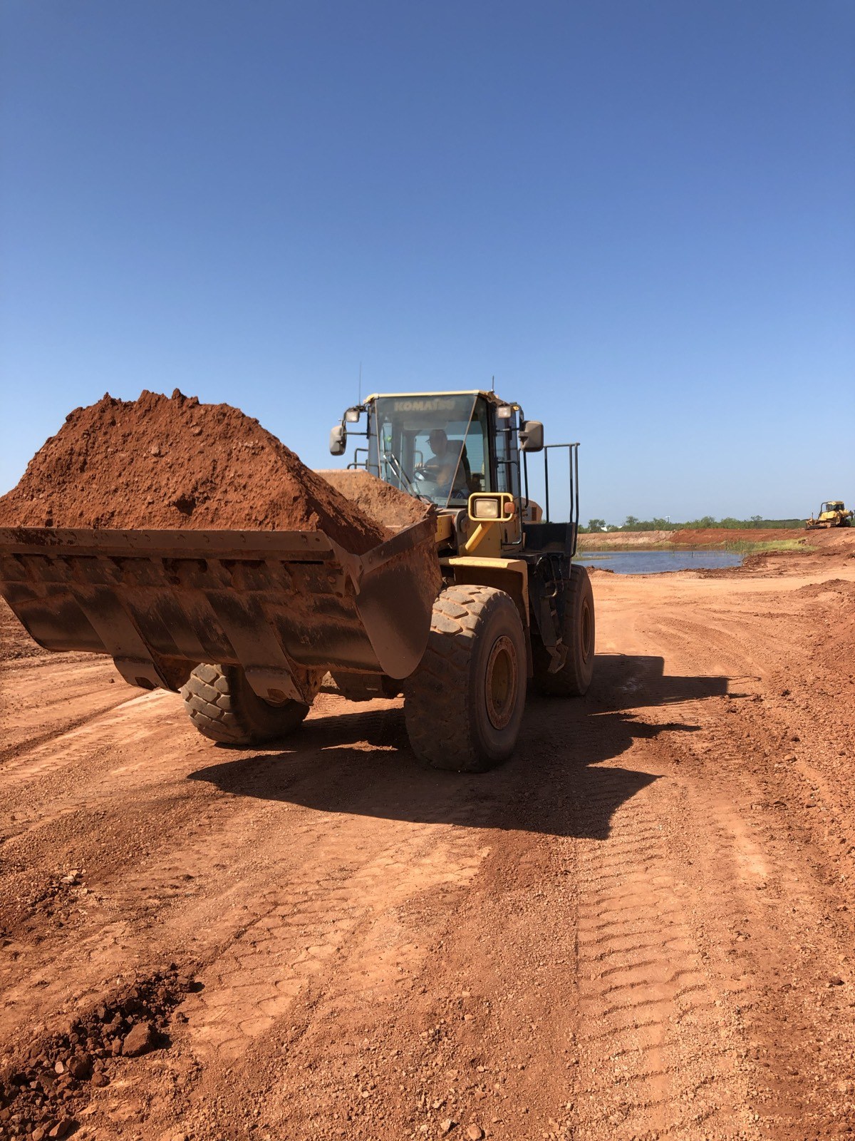 Wheel loader on site with pond visible