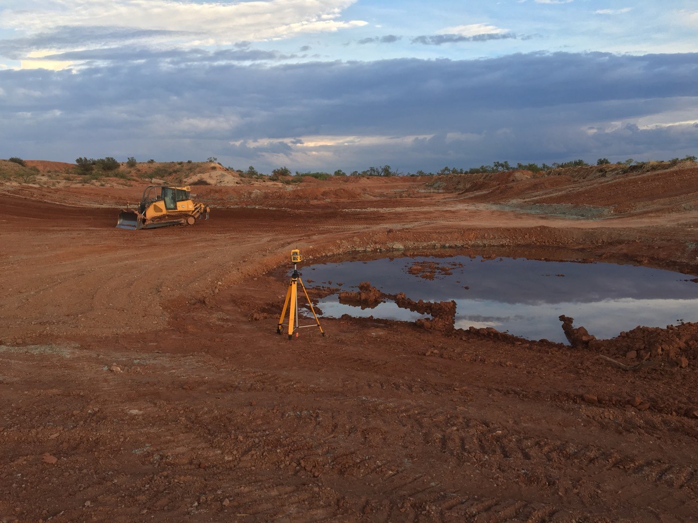 Dozer and grade control equipment near a pond in progress