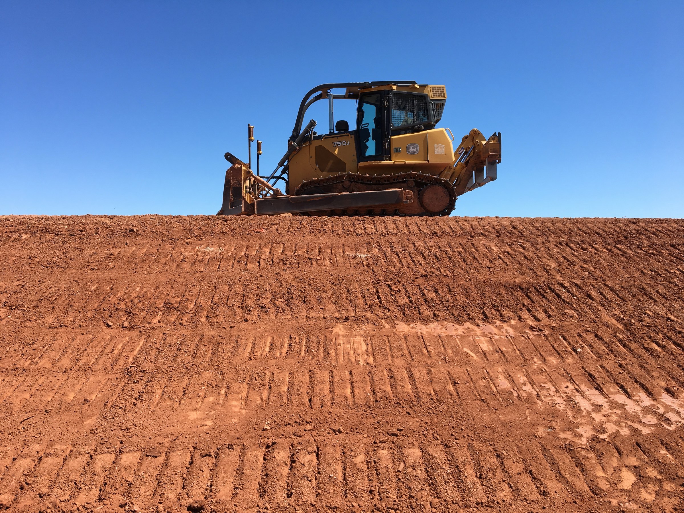 Dozer grading a building pad against open sky