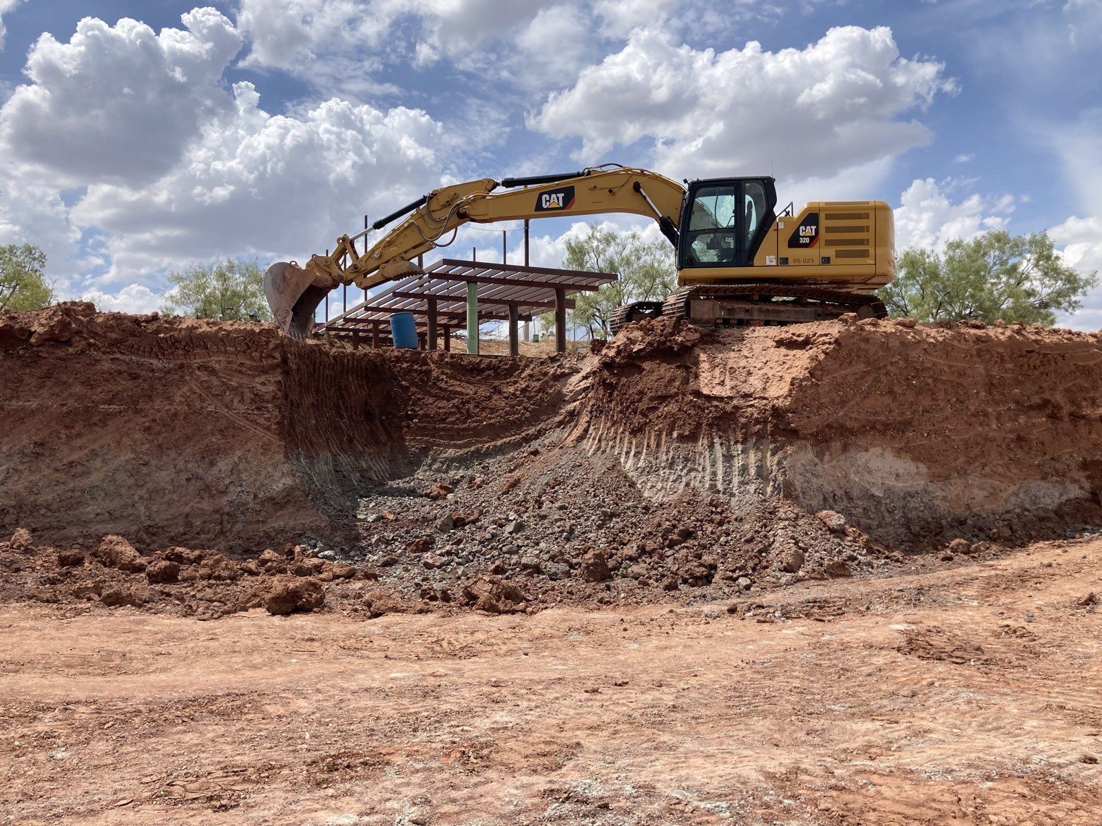 Excavator digging a trench near a building site