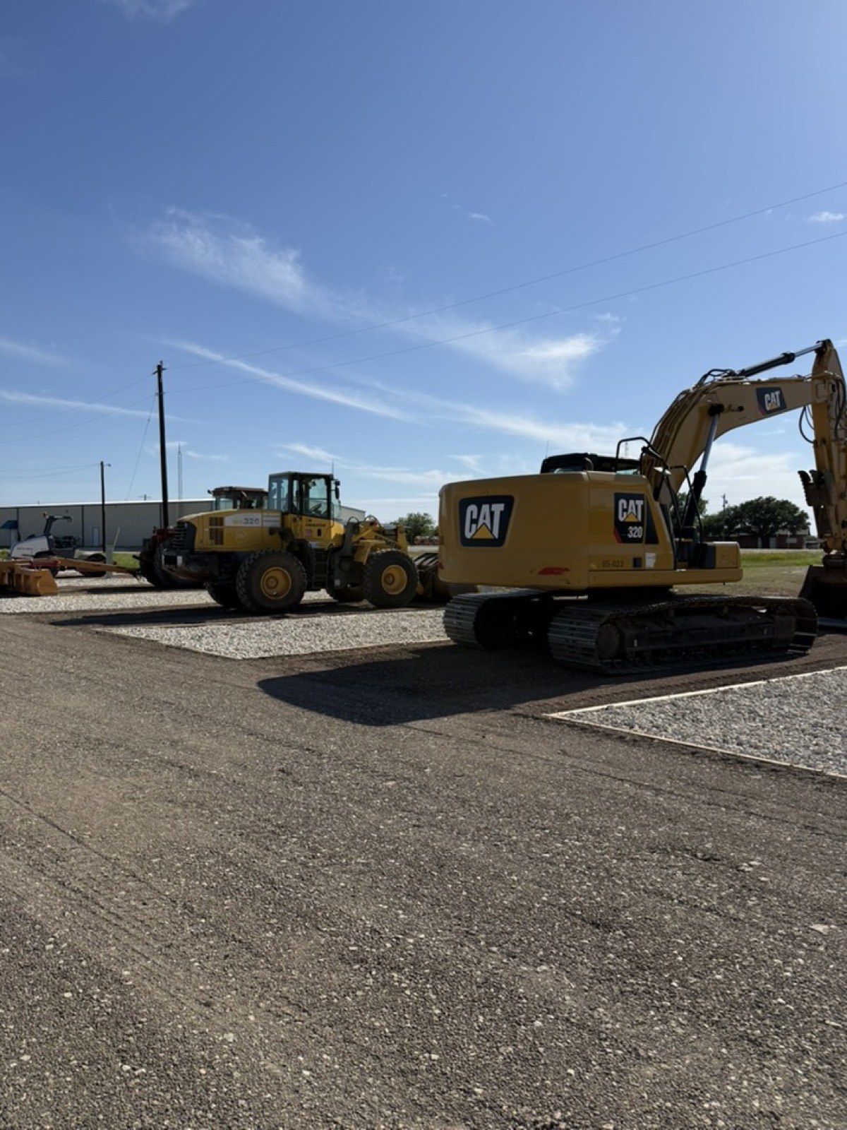 CAT excavator and wheel loader staged on a paved lot