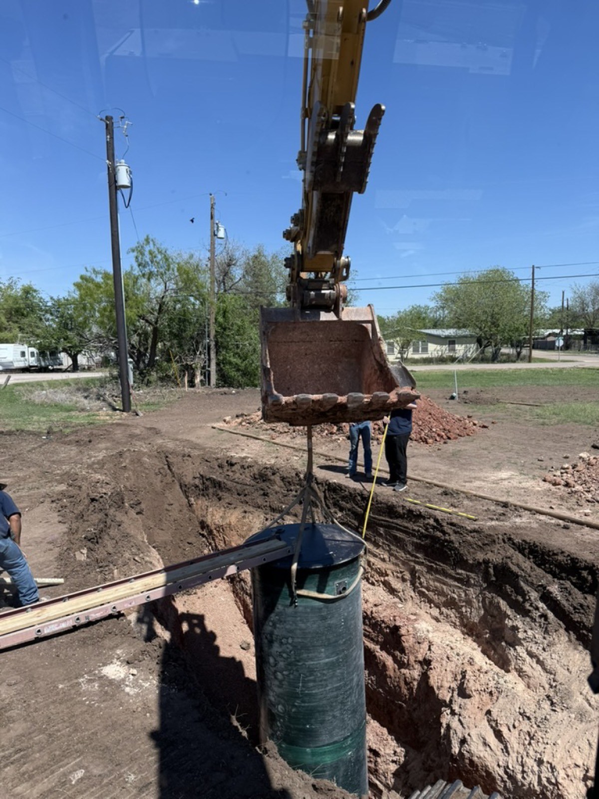 Excavator lowering a utility pipe into a trench